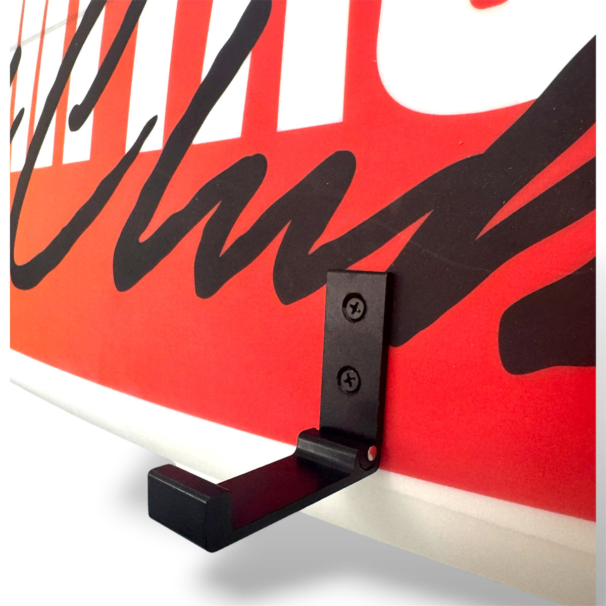 A close-up of a black metal hook mounted on a red and white surface with bold black script lettering.